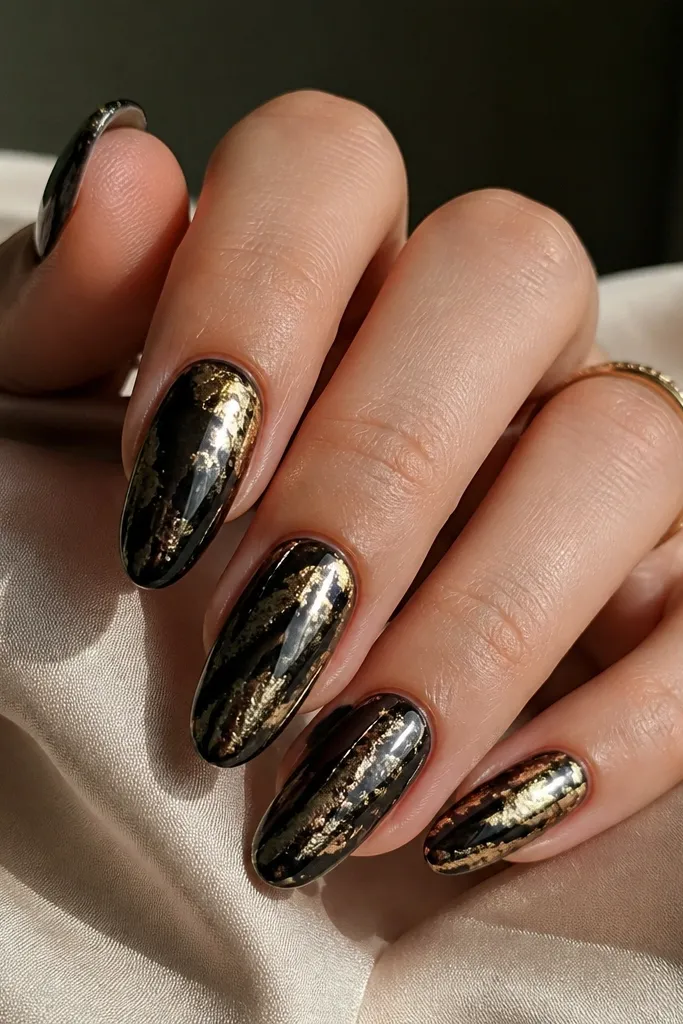 A layered look where thin gold leaf sits under a glossy black chrome layer; the gold peeks through near the center and edges like metallic veins.