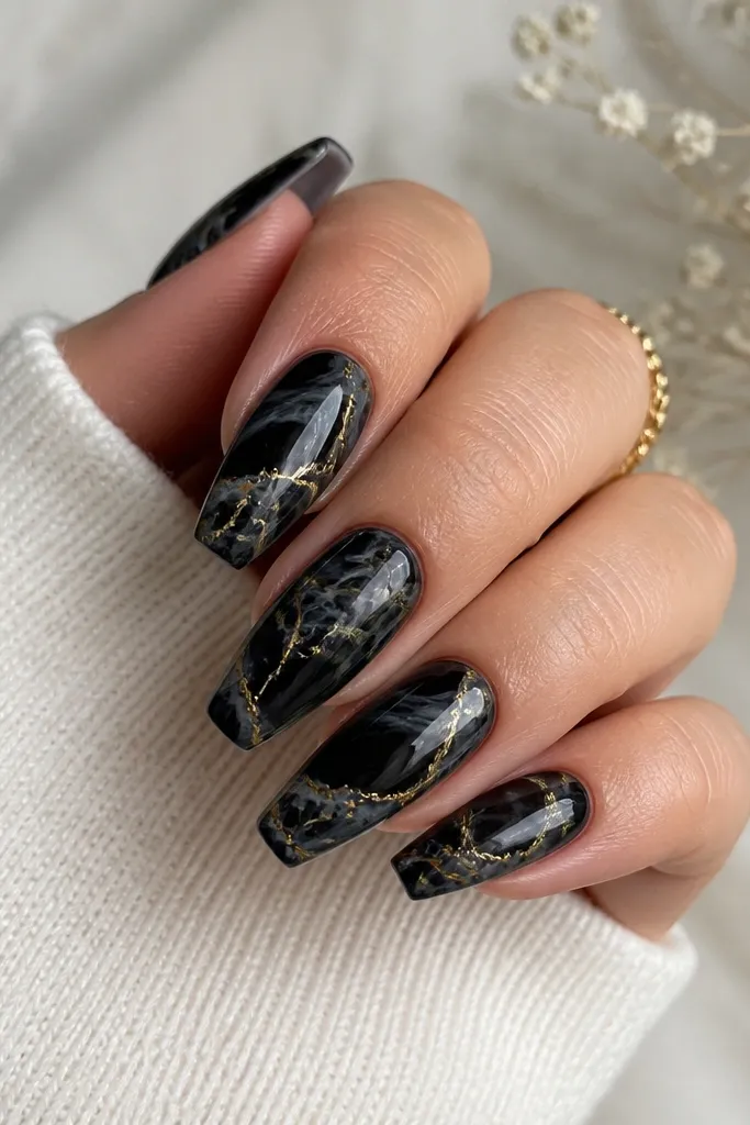 Medium coffin nails with smoky black marble swirls and thin gold vein lines running through the marble like cracked stone, finished with glossy topcoat.