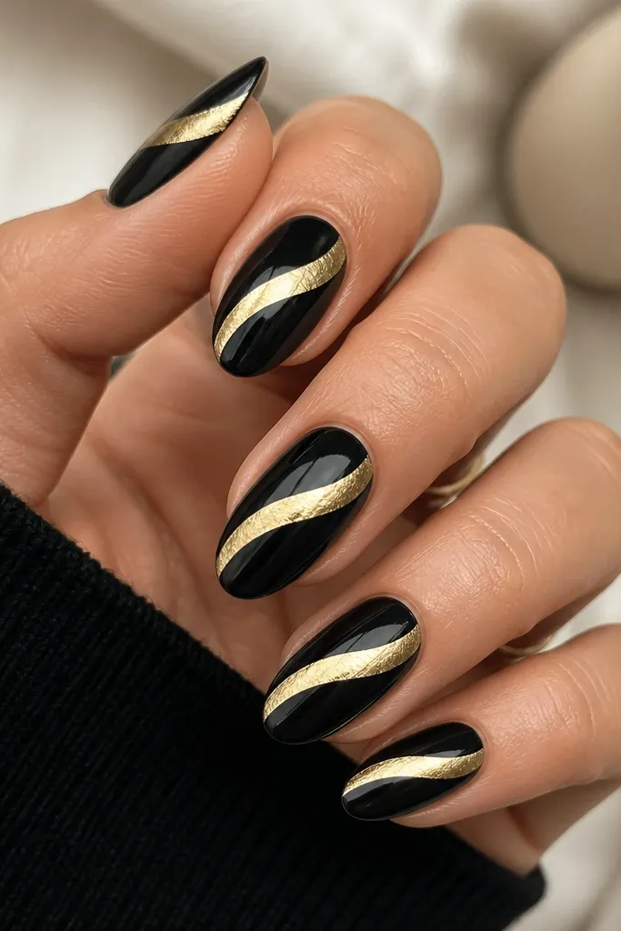 Medium oval nails with glossy black. Each nail has a single diagonal gold foil swoop from lower-left near the cuticle to upper-right toward the tip. The swoop is curved and slightly thicker at the center.
