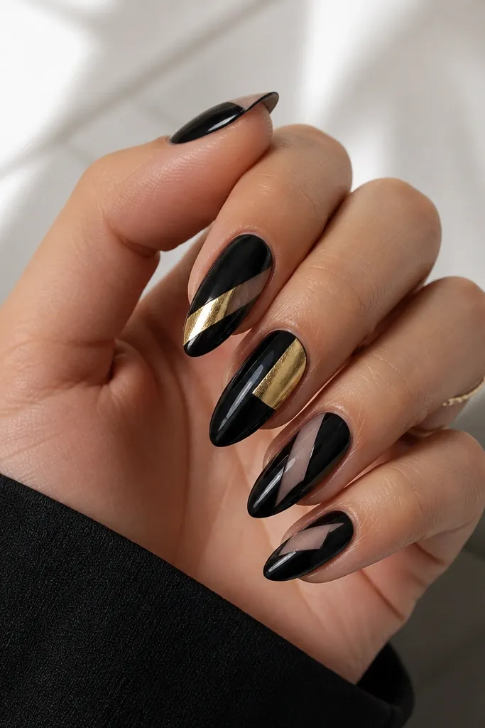 Black nails with sharp geometric shapes: a gold diagonal block on two nails, black triangles on others, and small nude negative-space windows. Edges are crisp and glossy.