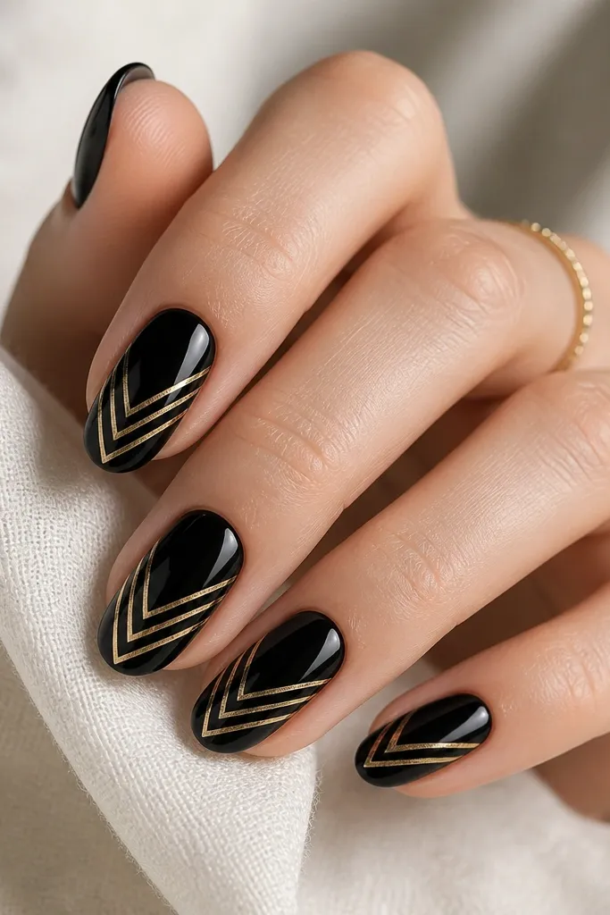 Each nail has a glossy black base. In the center there's a gold chevron made from thin lines, with clear negative space between the lines so the nail shows through. The chevron points toward the tip.