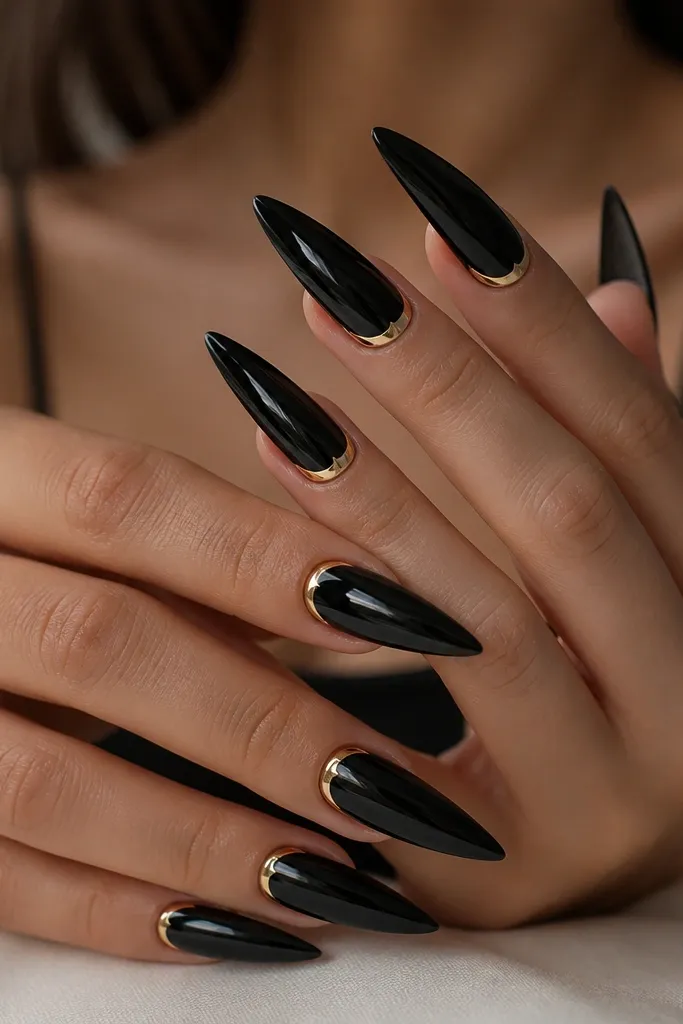 Long stiletto nails in mirror black with a thin gold arc centered right along the cuticle line on each nail; the gold forms a clean halo and the rest stays glossy black.