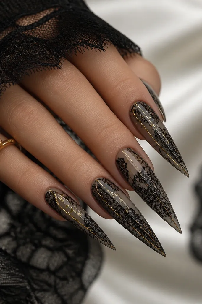 Long stiletto nails with black lace pattern over a sheer base; thin gold lines trace parts of the lace and run vertically like thread.