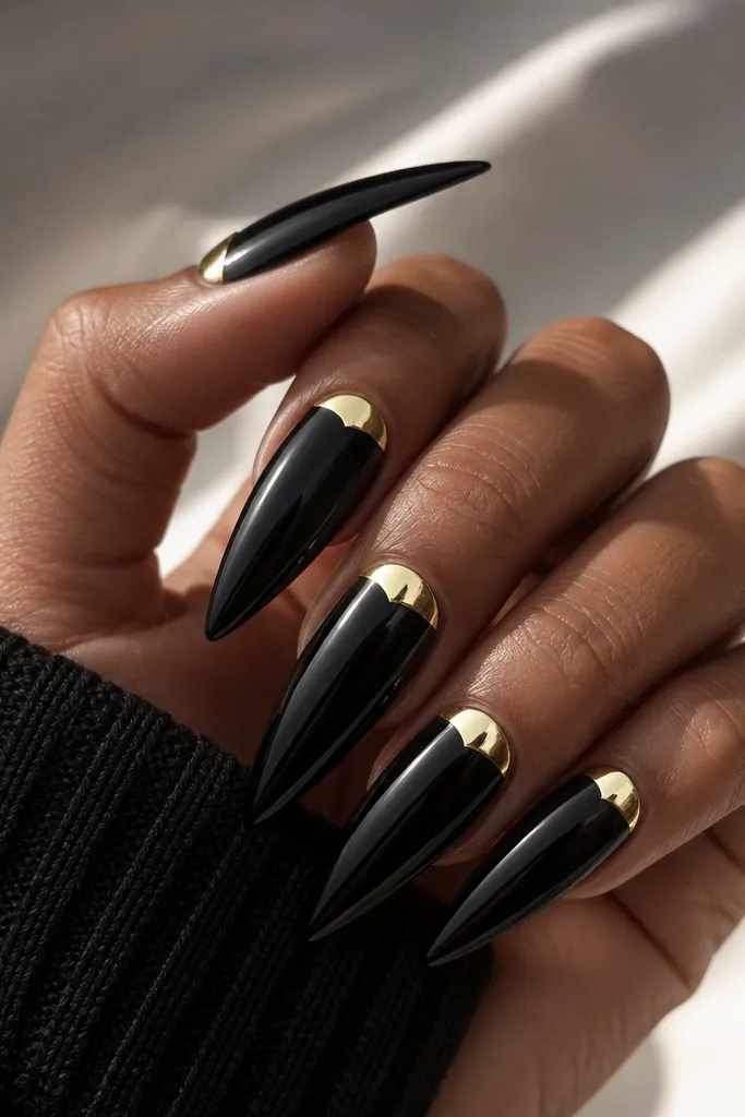 Stiletto nails with full glossy black coverage; a bright gold chrome half-moon sits at the cuticle center on each nail, with a clean curved edge.