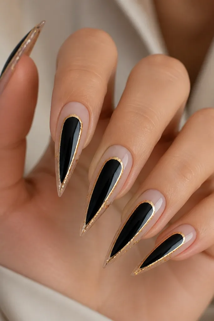 Stiletto nails with glossy black center panel; gold foil forms a thin rectangular frame around the black area, leaving the rest of the nail sheer/nude.