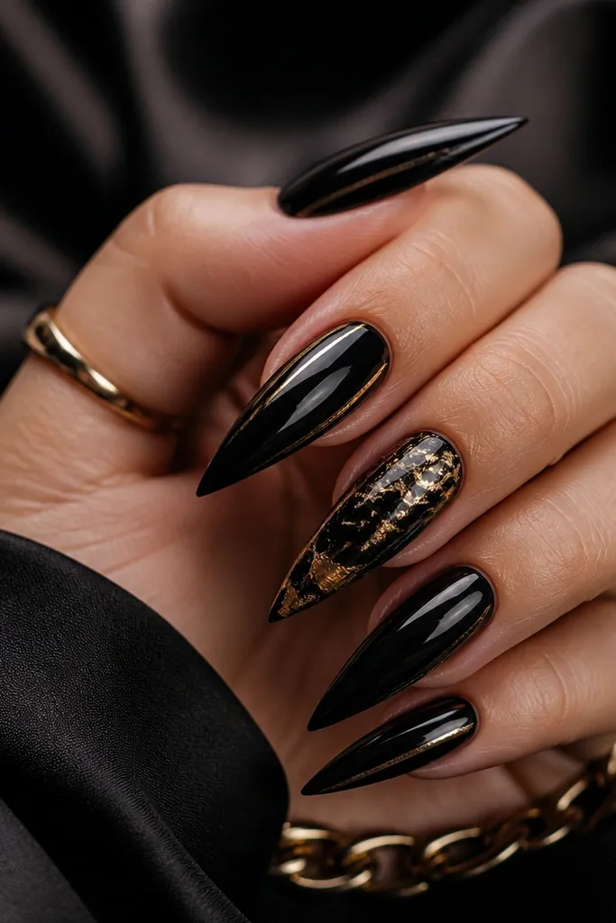 Four nails in glossy black with minimal gold; one accent nail has black marble swirls with gold foil patches and thin gold lines near the tip.