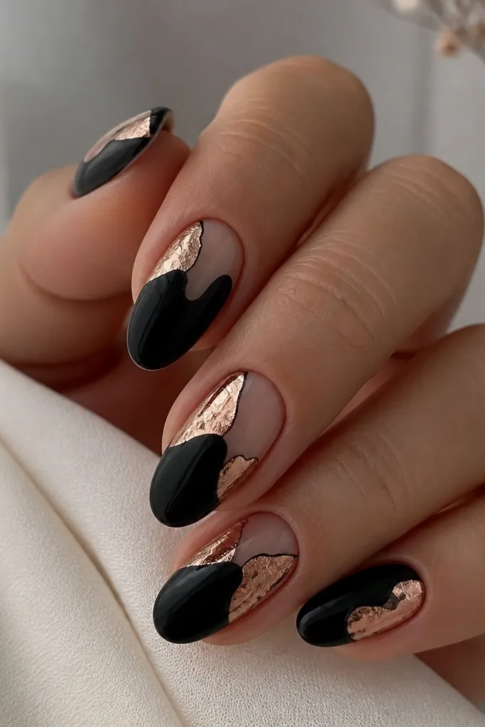 Black nails with clear negative-space sections. Rose-gold foil leaf is placed in irregular shapes over the negative areas, with thin black borders around the edges.