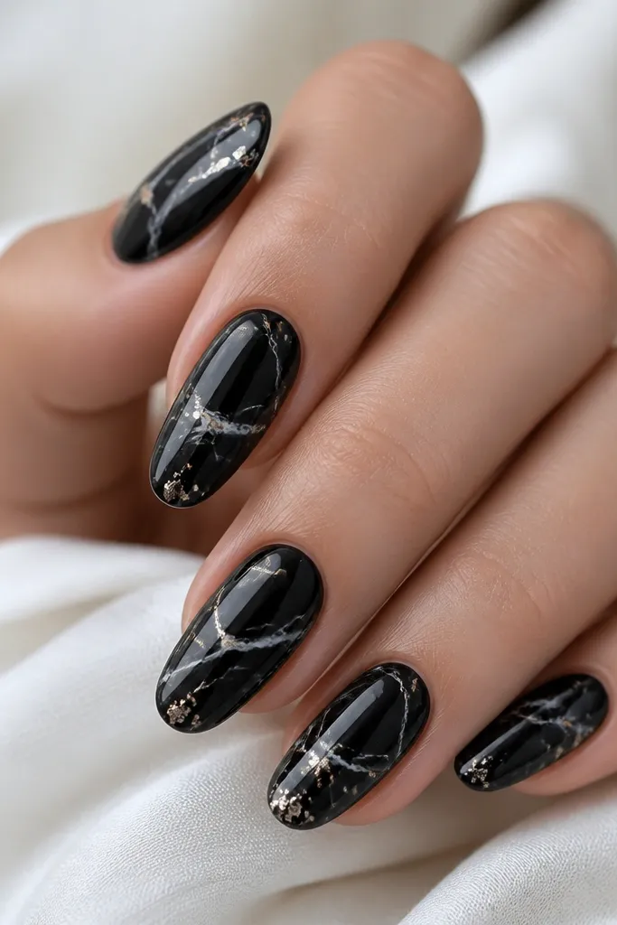 Black nails with thin, curved marble veins in charcoal and white. Tiny rose-gold flecks are sprinkled near the veins, mostly toward the center and near the tips.