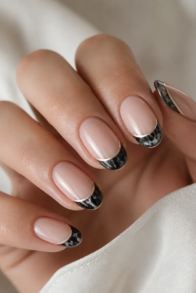 A nude base with a marbled black French tip. Along the very edge of the tip is a thin rose-gold metallic line that frames it like a border.