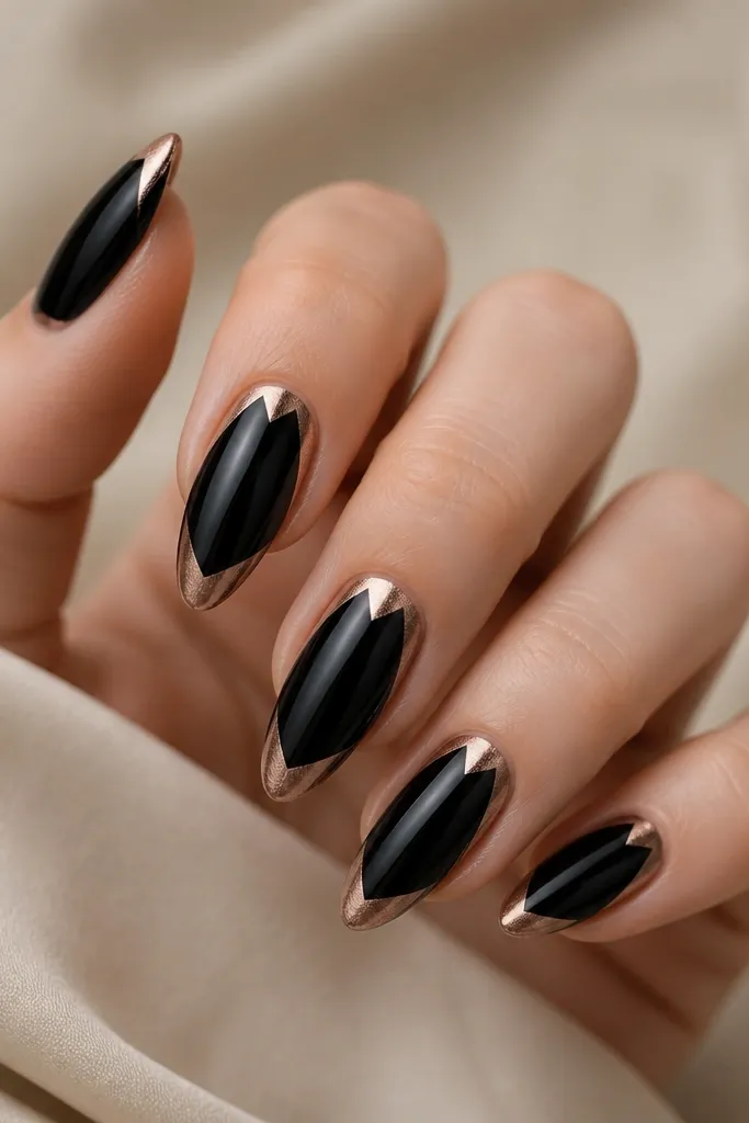 Black nails with a sharp V shape at the tip made from rose-gold metallic gel. The V points upward toward the center, with a clean, symmetrical line on both sides.