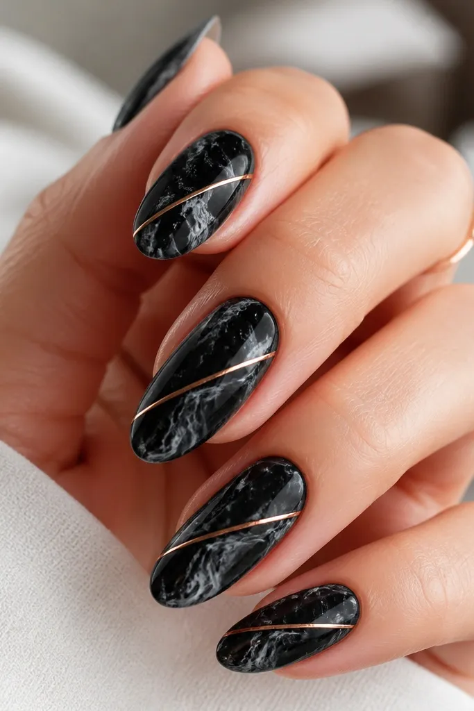 Black marble nails with charcoal and white swirls. A single thin stripe in rose gold runs diagonally across the nail, like a diagonal sash.