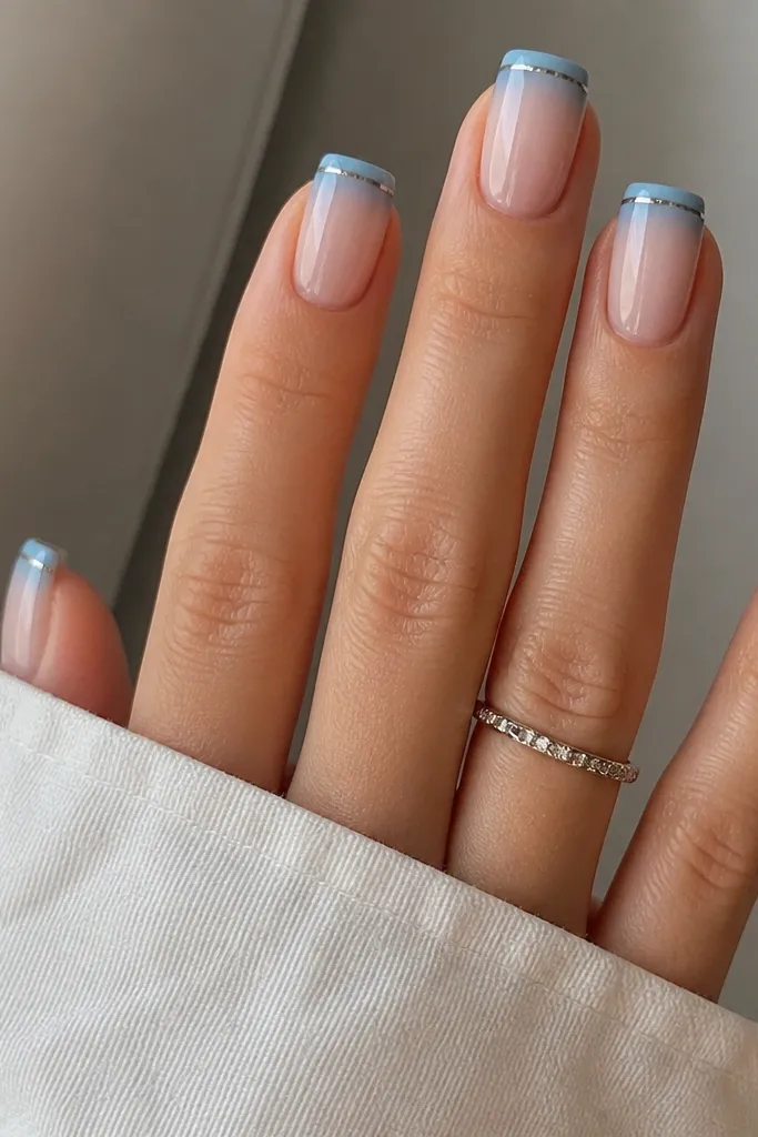Square nails with a soft denim-blue French tip that fades slightly at the inner edge. The outer tip border has a bright silver chrome line. The base is a milky nude, and the nails look glossy with clean, straight edges.