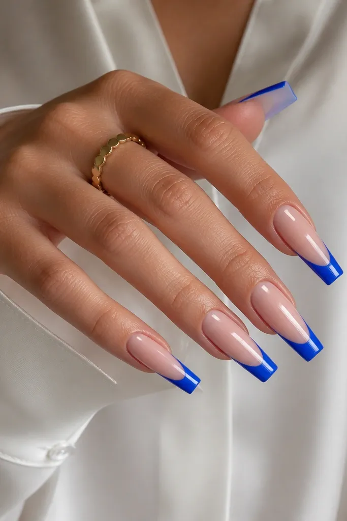 Long coffin nails with a classic painted blue French tip. The finish is glossy but not mirror-chrome. The base is sheer nude with a clean, thick smile line.