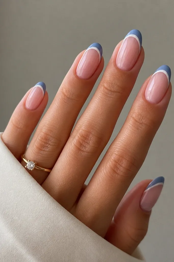 Medium almond nails with sheer pink base. Blue French tips are classic width and shape, and a thin white border runs along the inner edge of the blue tip.