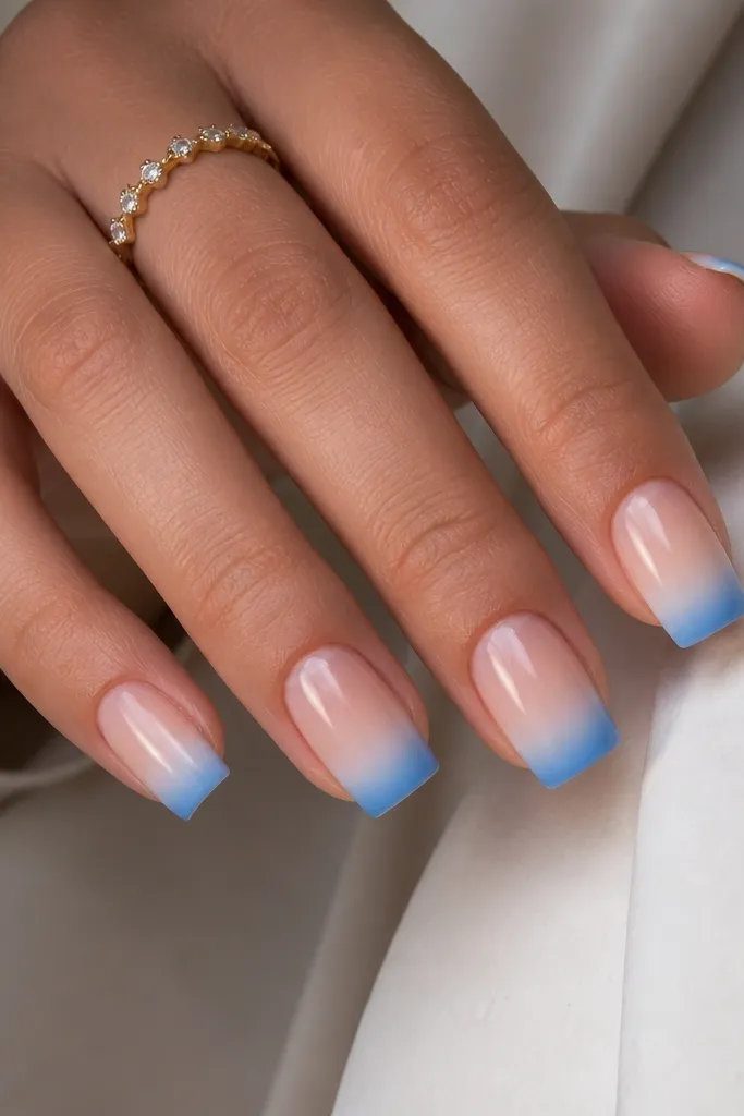 Square nails with a sheer nude base. The French area starts deeper blue at the edge and fades into a milky white near the smile line. The gradient looks smooth with no harsh streaks.