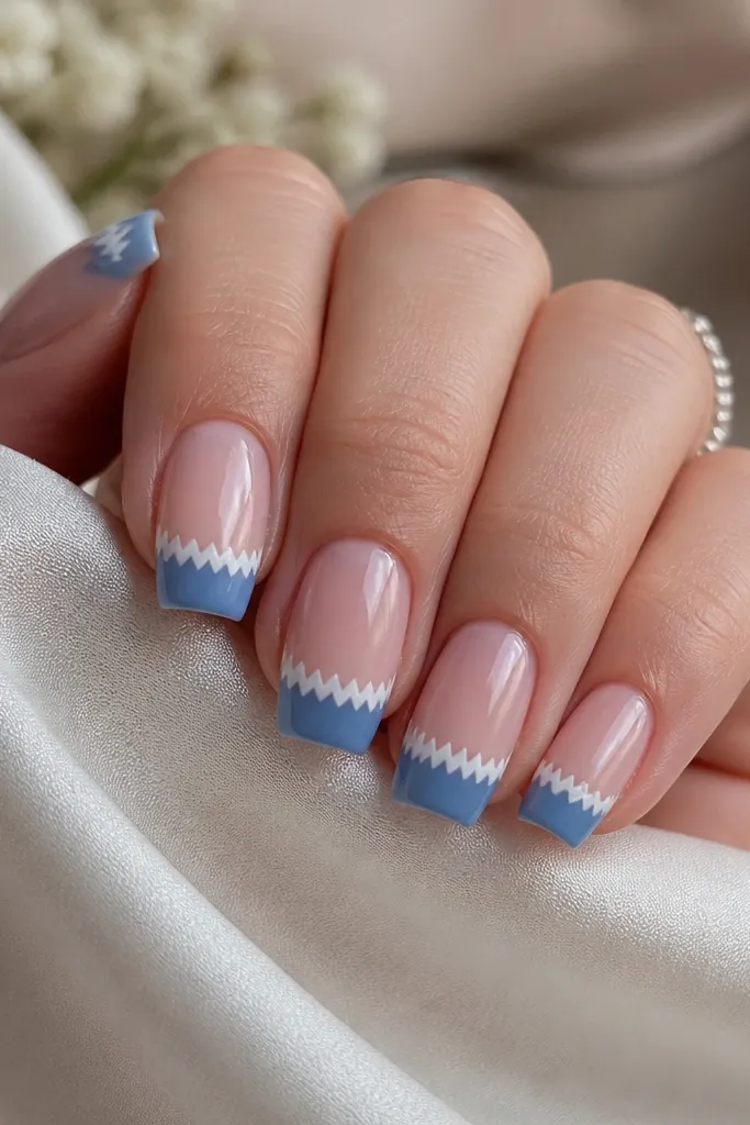 Medium square nails with a sheer nude base. Blue French tips have a white lace-like zigzag edge created by tape lines, with tiny repeating peaks along the border. Glossy finish.