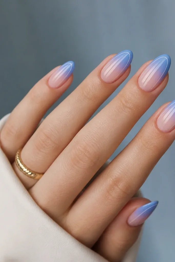 Medium almond nails with a blue ombré tip that fades upward; two thin white stripes run along the left and right sides of each nail.