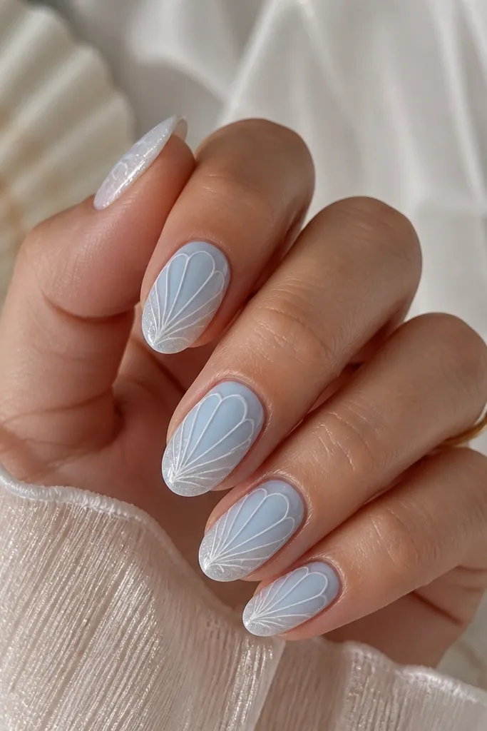 Short almond nails in milky pastel blue. The shell ridges are raised with a white 3D gel outline, and there's a faint shimmer at the free edge.