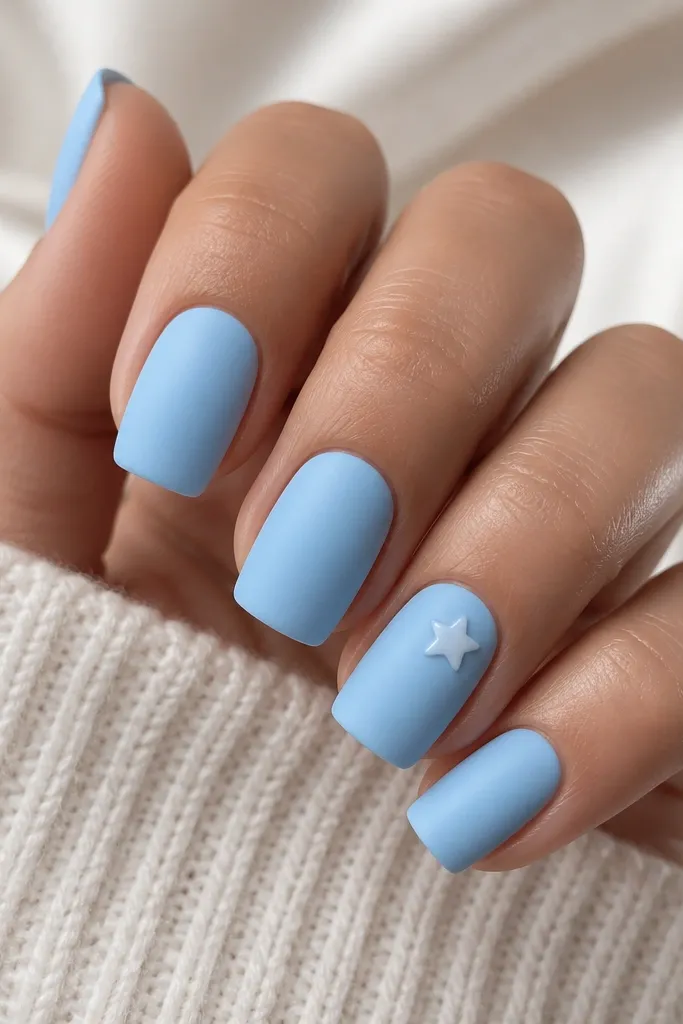 Square nails in sky blue matte finish. One nail has a small glossy white star near the cuticle, and the star has a raised shine. Other nails have no art.