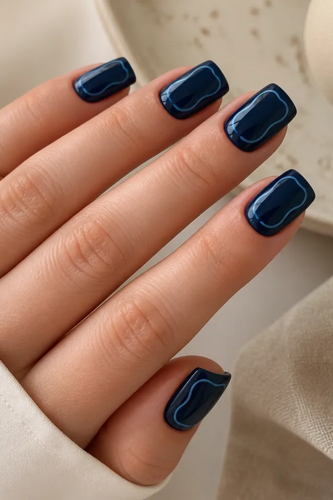 Square nails with a deep midnight blue glossy base. On each nail, a light blue outline traces a curved shape around the center, like a soft frame. The outline is thin and clean.