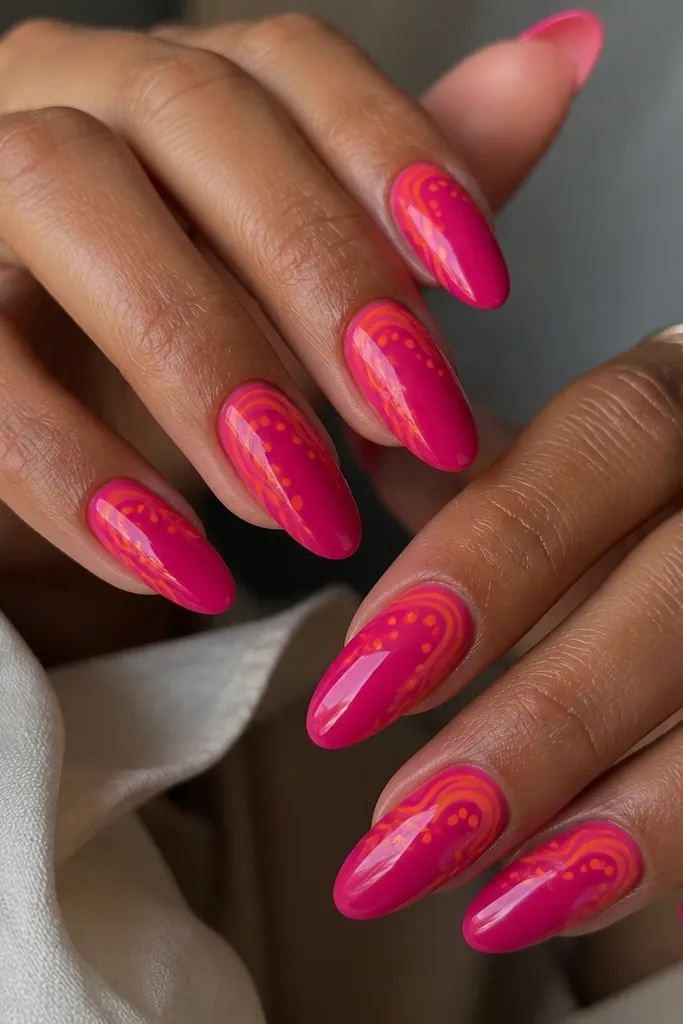 Glossy hot pink nails with thin white-ish negative lines? Actually hot pink base with curving orange swirls near the cuticle and small tangerine dots scattered along the swirl path.
