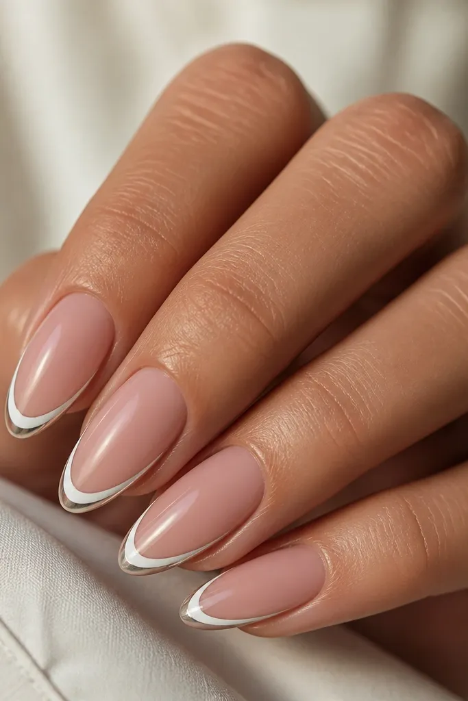 Almond nails with a thin white French line and a second even thinner line just outside it in silver chrome, creating a two-tone outline glow.
