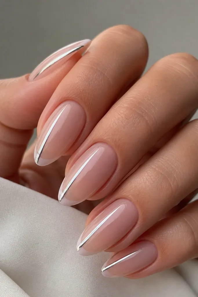 Almond nails with thin white French tips; one side edge has a vertical chrome stripe running from near the cuticle to the tip, while the rest is glossy clear or nude.