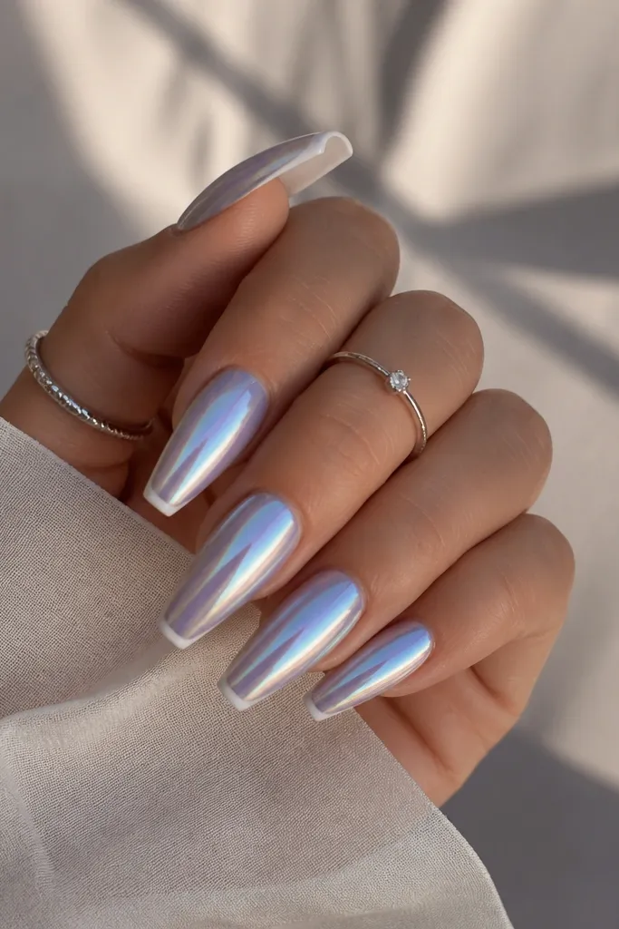 Coffin-leaning almond nails with thin white French tips; the chrome shows a silver base with subtle blue-purple shifts as the angle changes.