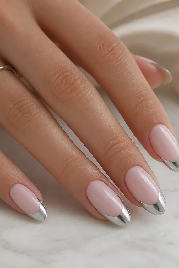 Medium-length almond nails with a milky pink opaque base. French tips are wide, about 3mm, in silvery chrome with a sharp curved border, glossy and smooth.