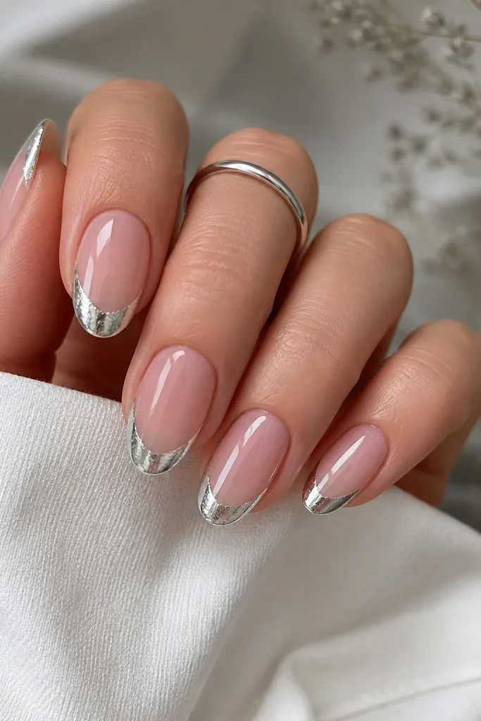 Medium oval nails with a clear pink base. Silver chrome French tip looks like it has a slightly foil-crinkled edge at the outer border, still glossy and smooth overall.