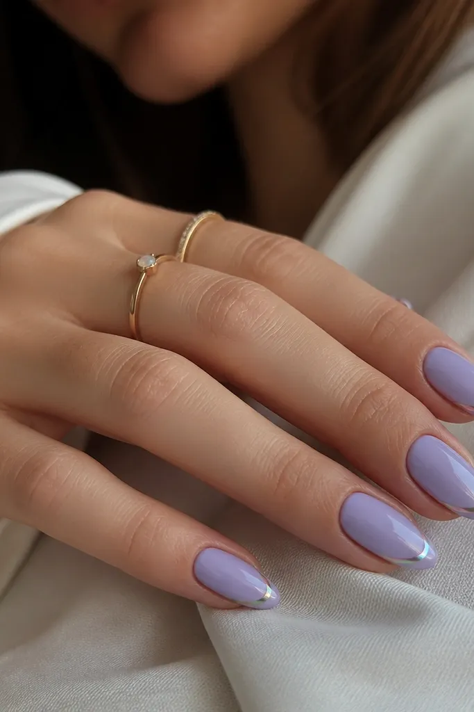 Almond nails with a soft lavender base. The French line is a thin holographic chrome strip that flashes pink, green, and blue as it curves.