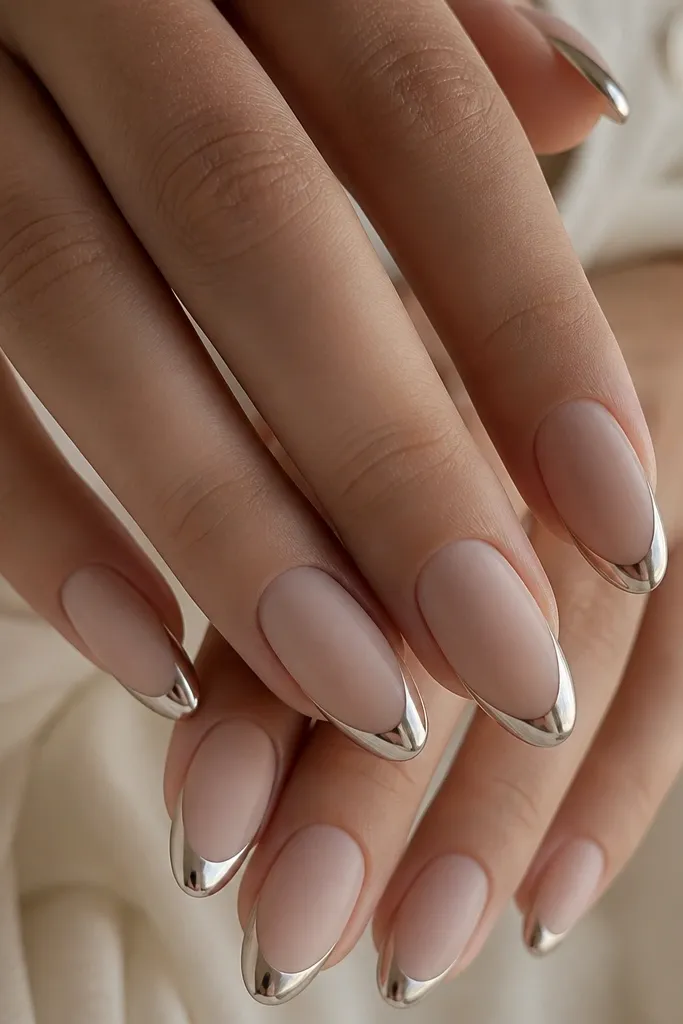 Medium almond nails with matte nude base and glossy chrome French tips, mirror shine popping against the matte.