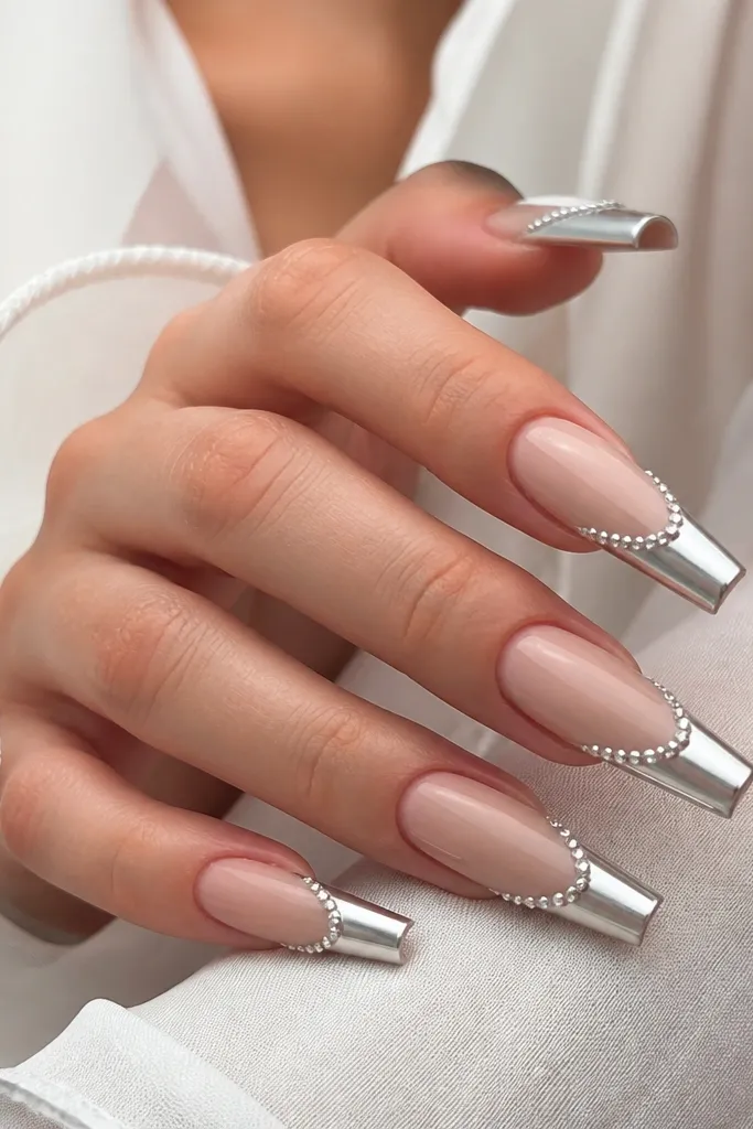 Long coffin nails with nude base, chrome French tips, and a thin row of micro rhinestones along the border.