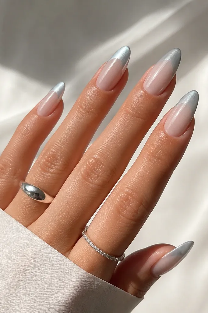 Almond nails with a translucent clear jelly nude base. The French tip is icy silver chrome that fades into the clear base, creating a frosty gradient. The nails look glossy and glass-like.