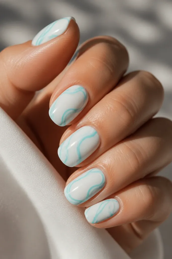 Milky white base with thin aquamarine swirl lines that curve across the nail; the swirls look hand-drawn but crisp, with a high-gloss finish.