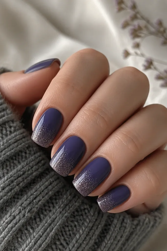 Blueberry purple nails with a sheer silver glitter fade that starts at the tip and fades upward; glitter is subtle and sparkly, not chunky.