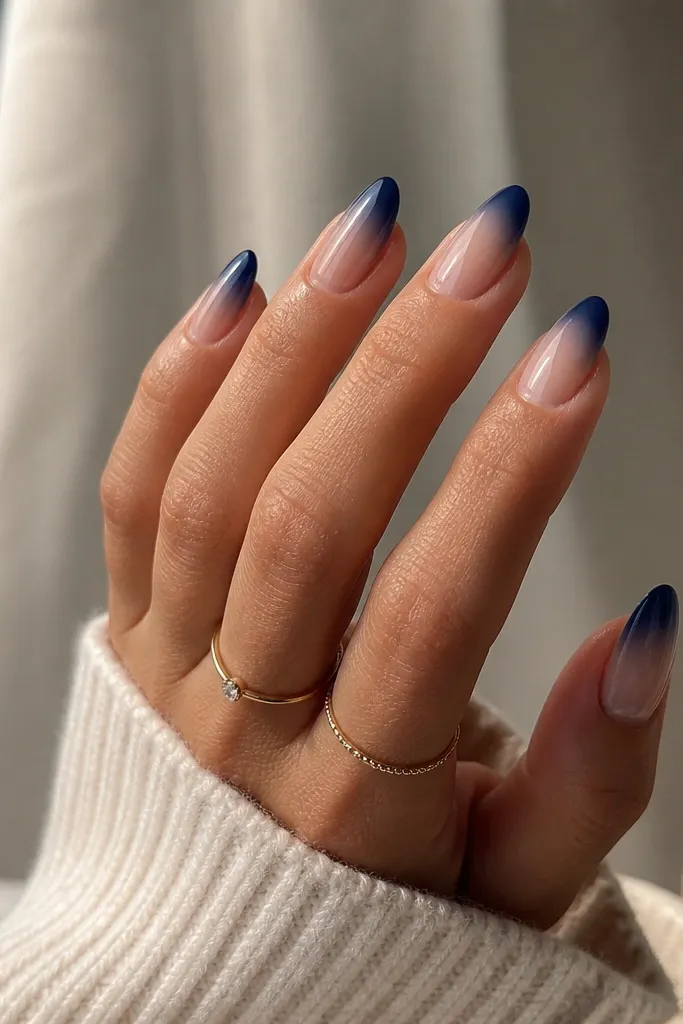 Medium-length nails with a nude base and a smooth ombre effect where navy fades upward into the nail, forming a French-style curve.
