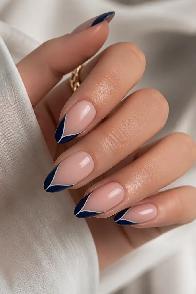 Almond nails with navy French tips; a thin diagonal stripe in white runs down the center of the blue tip, glossy finish.