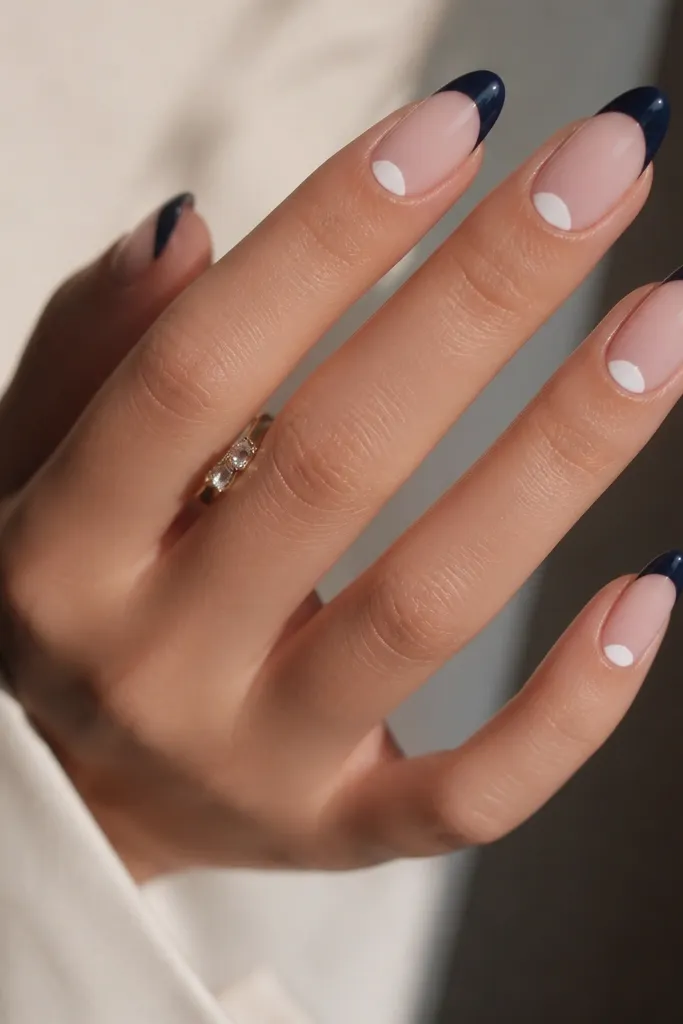 Medium almond nails with navy French tips; a white half-moon sits at the cuticle area on every nail, glossy finish.