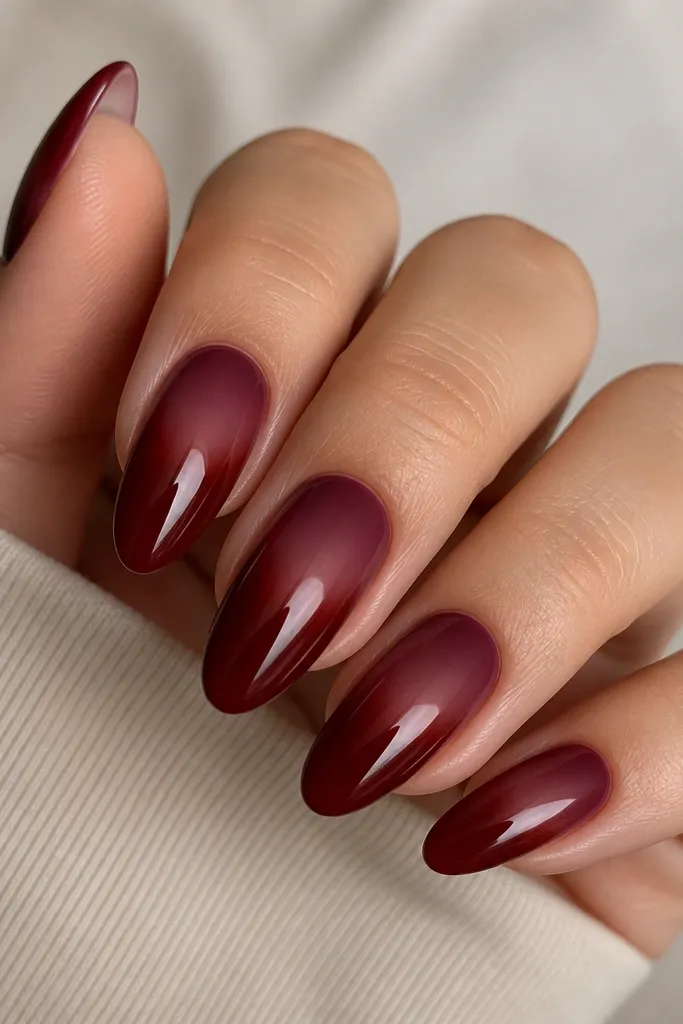 Dark cherry red acrylic nails with a glossy body but a matte, velvety fade starting at the cuticle and fading out toward the middle. The nails are almond-shaped and show a soft gradient effect.