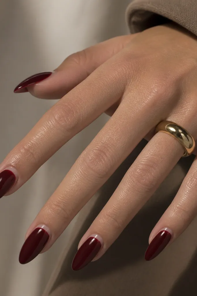 Long almond nails with a deep cherry red full coverage. The cuticle area has a thin clear cap that looks like a glossy halo, and the rest is mirror shine.