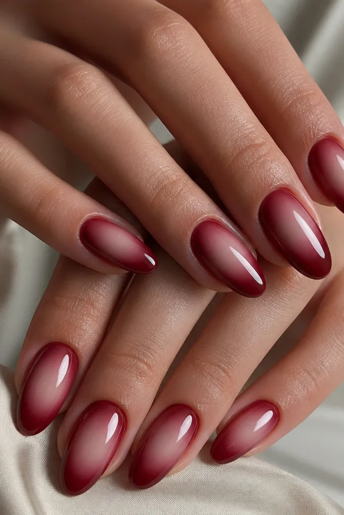 Nude center area on each nail with a soft aura glow blending into dark cherry red edges, glossy, almond nails.