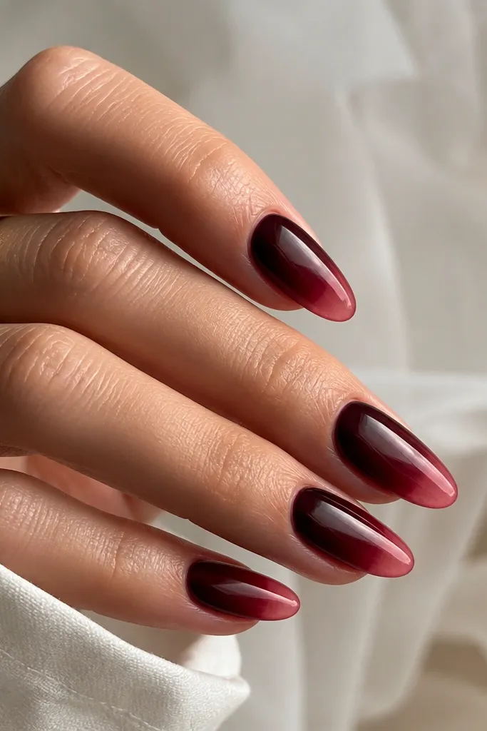 Medium almond nails with a dark cherry red base that fades into a translucent jelly tip. The tips look slightly lighter and see-through, with the gradient ending before the sidewalls.