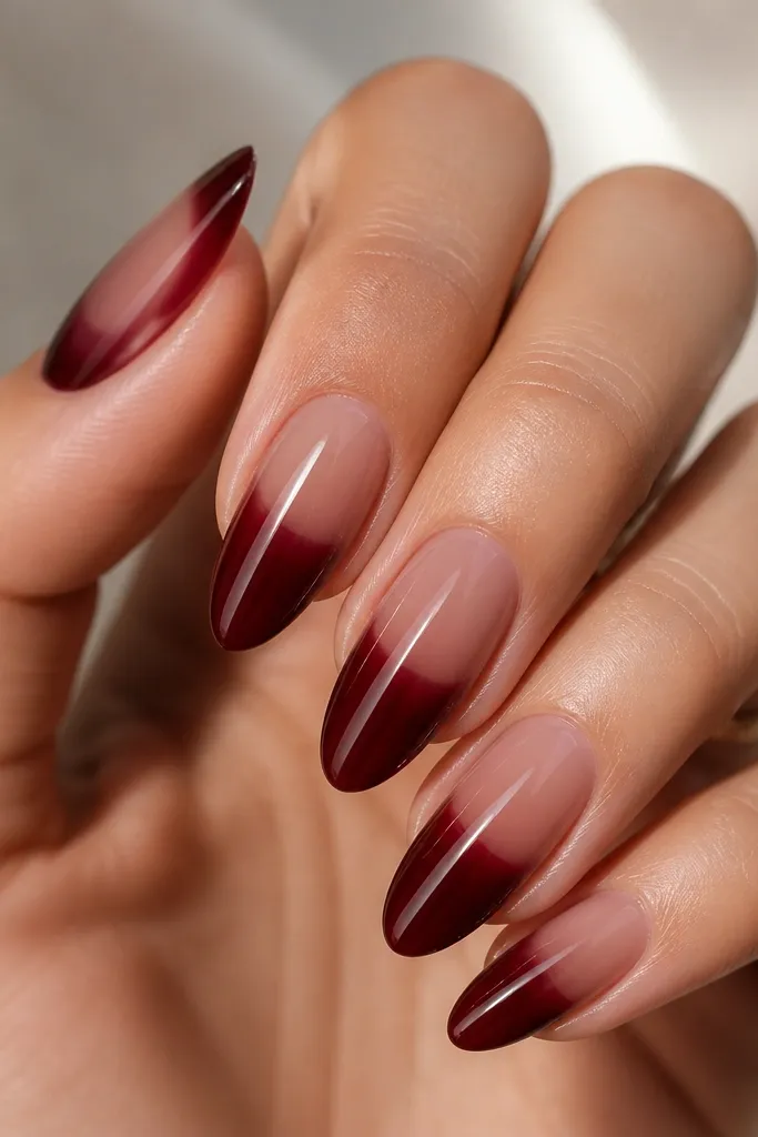 Almond nails where the lower half is glossy dark cherry red and the upper half has a translucent clear gel glaze with a faint cherry tint. The boundary line is soft and curved.