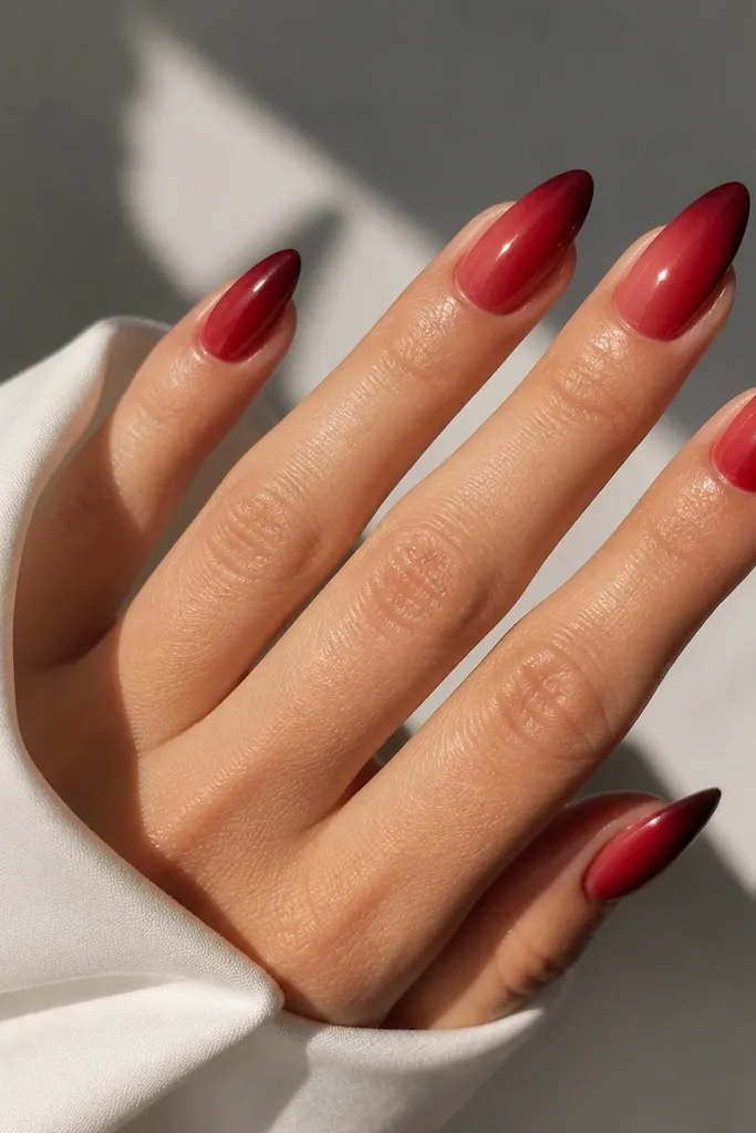 Almond nails with a gradient that starts as a lighter cherry near the cuticle and deepens to a dark cherry at the tip. The fade is smooth with no harsh banding.