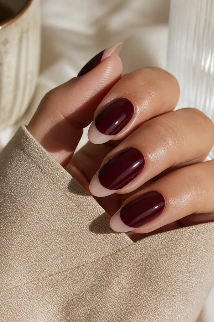Almond nails with a dark cherry base that stops short of the tip, leaving a nude strip at the free edge. The boundary line is crisp and glossy.