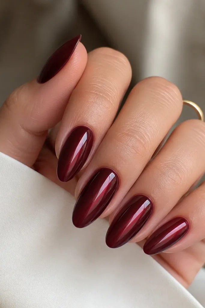 Almond nails where the center strip is sheer jelly dark cherry, and the sides are more opaque dark cherry. The center looks lighter and glassy, creating a vertical highlight.