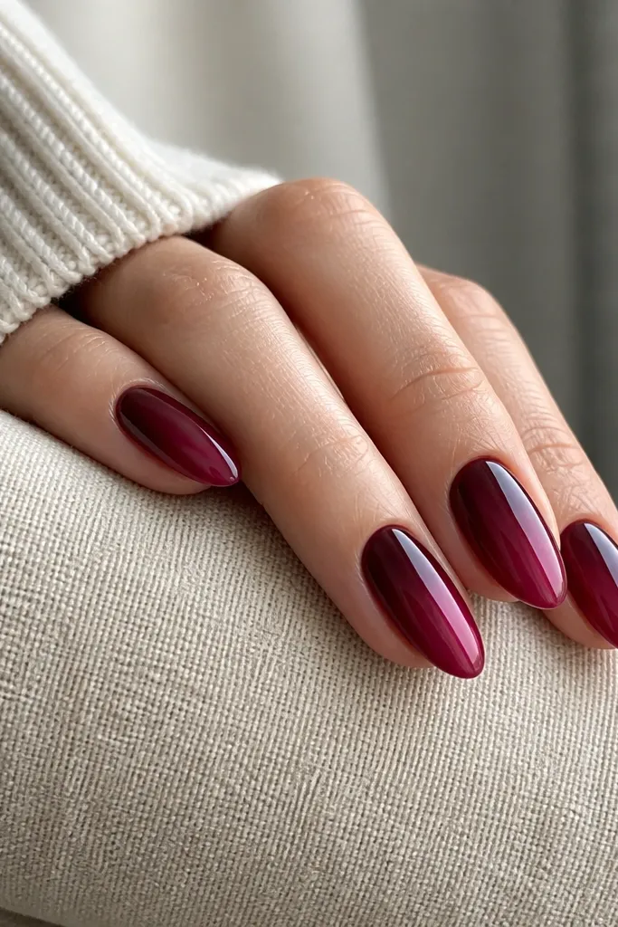 Almond nails in dark cherry red with a lighter berry gradient swipe on one side of each nail, running from near the middle toward the tip. The swipe looks smooth and glossy.