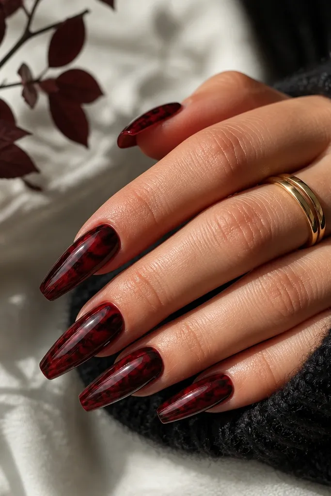 Coffin nails with a dark cherry red base and marbled swirls in black and deeper burgundy, glossy with a smooth gel finish.