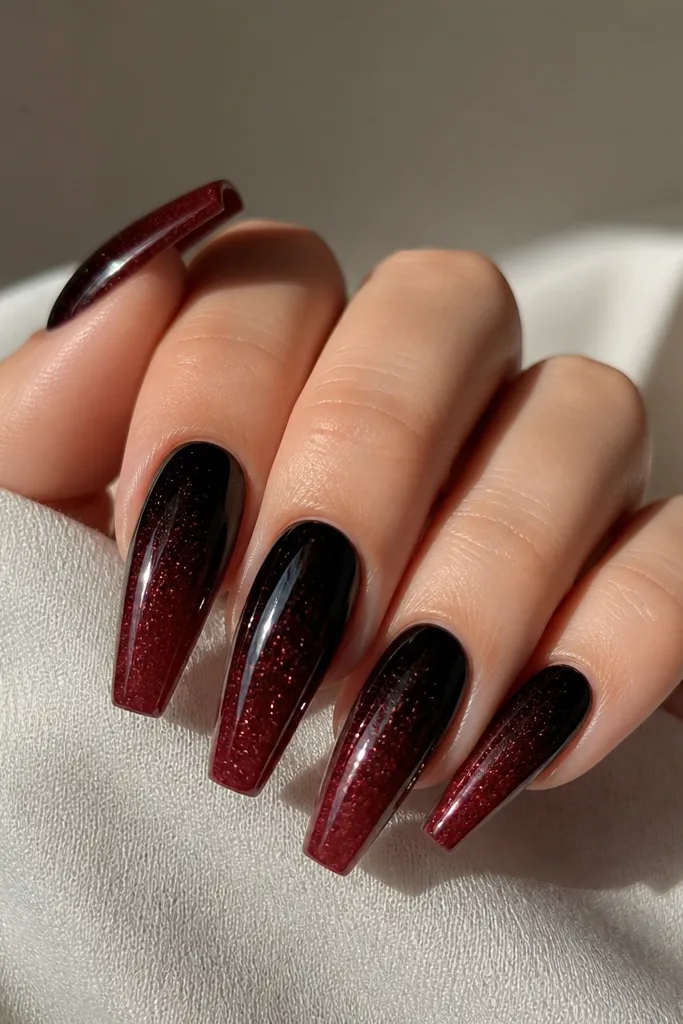 Coffin nails fading from near-black at the cuticle to dark cherry at the tip, with a light dusting of fine shimmer throughout, glossy.